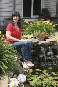 Beth sitting next to her backyard pond with a waterfall